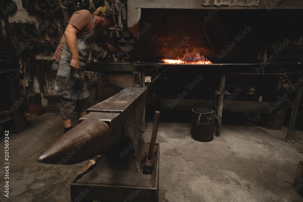 Blacksmith heating metal rod in fire Blacksmith heating metal rod in fire