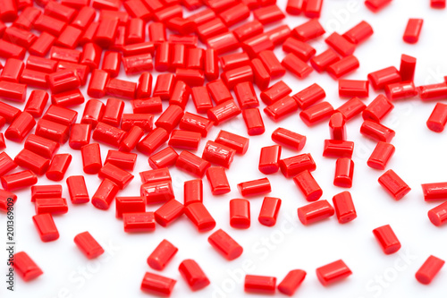 Red plastic polymer granules on white background.