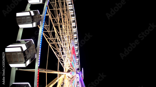 Fototapeta Naklejka Na Ścianę i Meble -  Side view of huge Ferris wheel rotating at amusement park under dark night sky