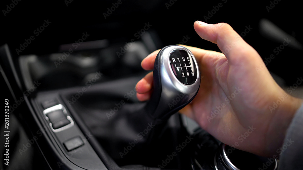 Αυτοκόλλητο Male hand holding manual gearbox in car, test drive of new automobile, closeup
