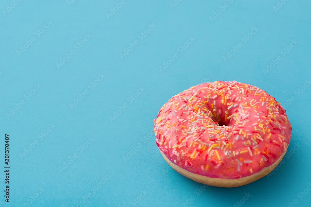 Pink frosted donut with colorful sprinkles on blue background. Copyspace Pink frosted donut with colorful sprinkles on blue background. Copyspace