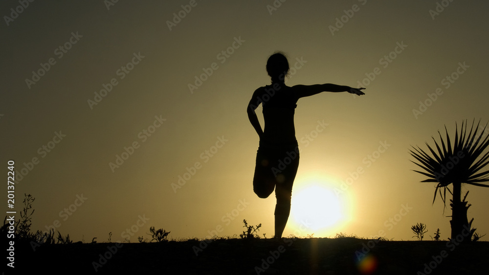 Silhouette of young woman stretching before doing exercises early morning