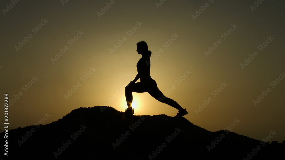 Woman with flexible body practicing yoga positions, doing exercises in mountains