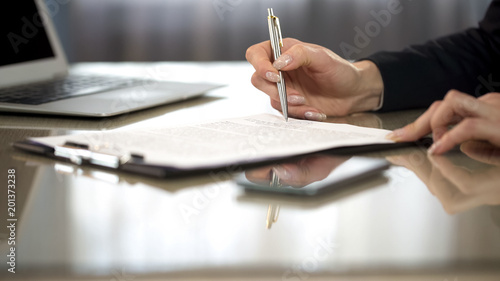 Woman in suit reading terms and conditions of agreement, signing contract photo