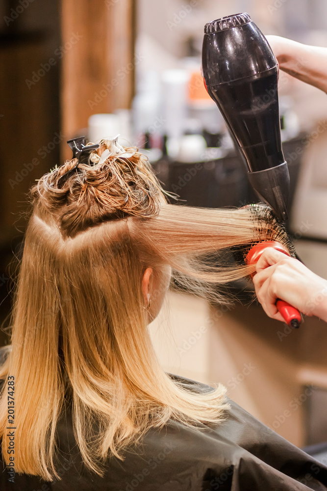 Fototapeta premium hairdresser stylist dries wet hair with hair dryer