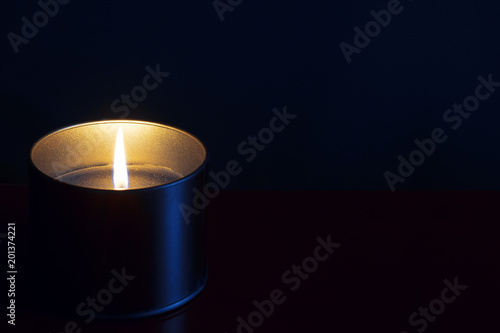 Burning yellow candle isolated on black background