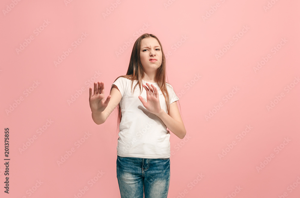 Doubtful pensive teen girl rejecting something against pink background Doubtful pensive teen girl rejecting something against pink background