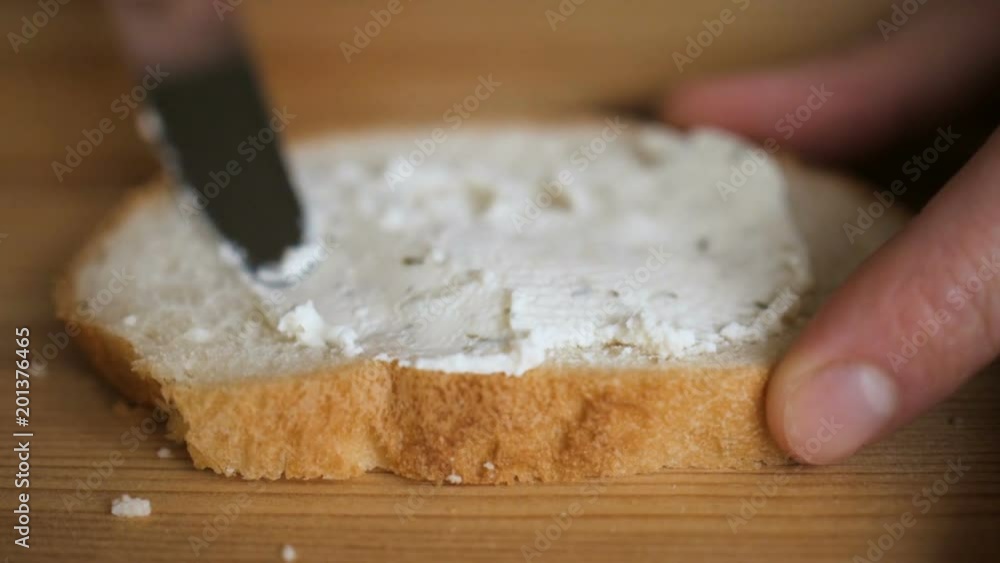 Man spreading butter on rye dry toast with a knife. Person spreading creamy butter on a piece of bread. Close up of male hands spreading butter on bread in kitchen, slow motion. Man spreading butter on rye dry toast with a knife. Person spreading creamy butter on a piece of bread. Close up of male hands spreading butter on bread in kitchen, slow motion.