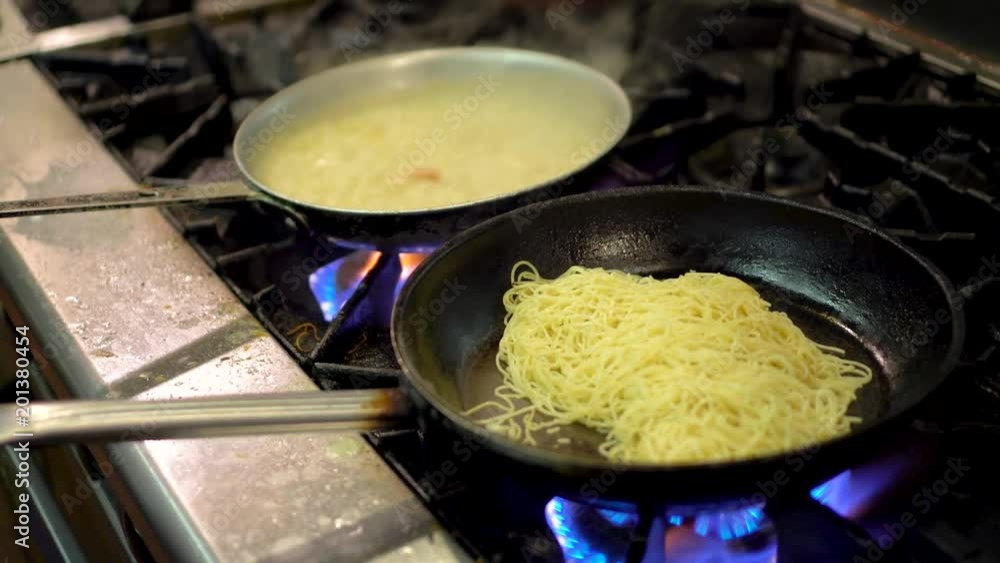Shrimp in garlic sauce bubbling on a fire and a chef moves the pan around. Shrimp in garlic sauce bubbling on a fire and a chef moves the pan around.