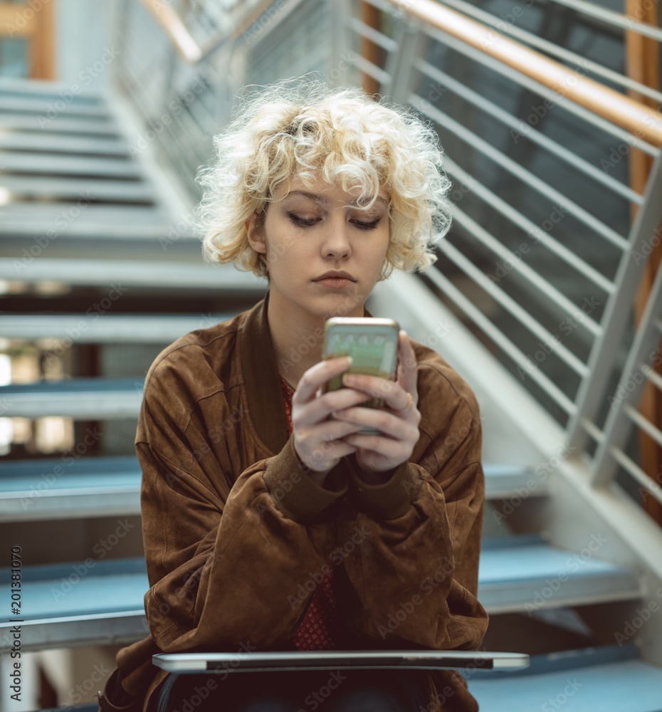Young woman using smartphone while sitting on stairs Young woman using smartphone while sitting on stairs