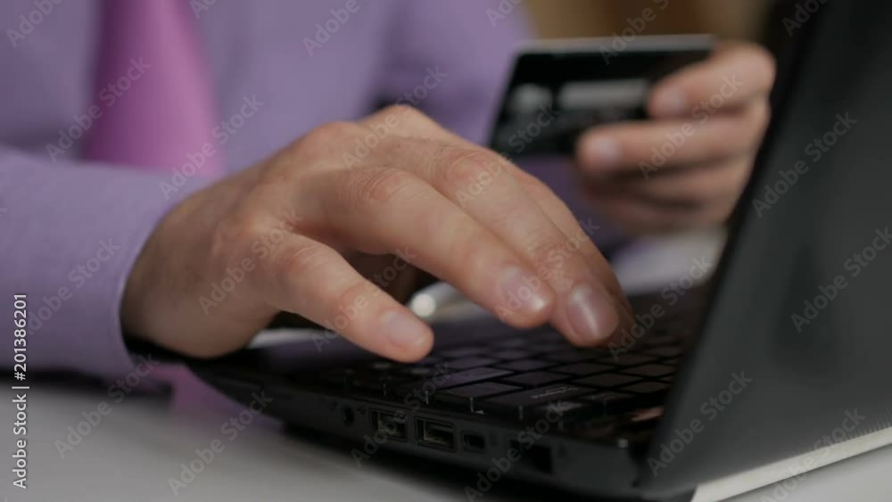 A businessman in a purple shirt and tie is making a payment to internet banking. Shopping online with credit card on laptop. A businessman in a purple shirt and tie is making a payment to internet banking. Shopping online with credit card on laptop.