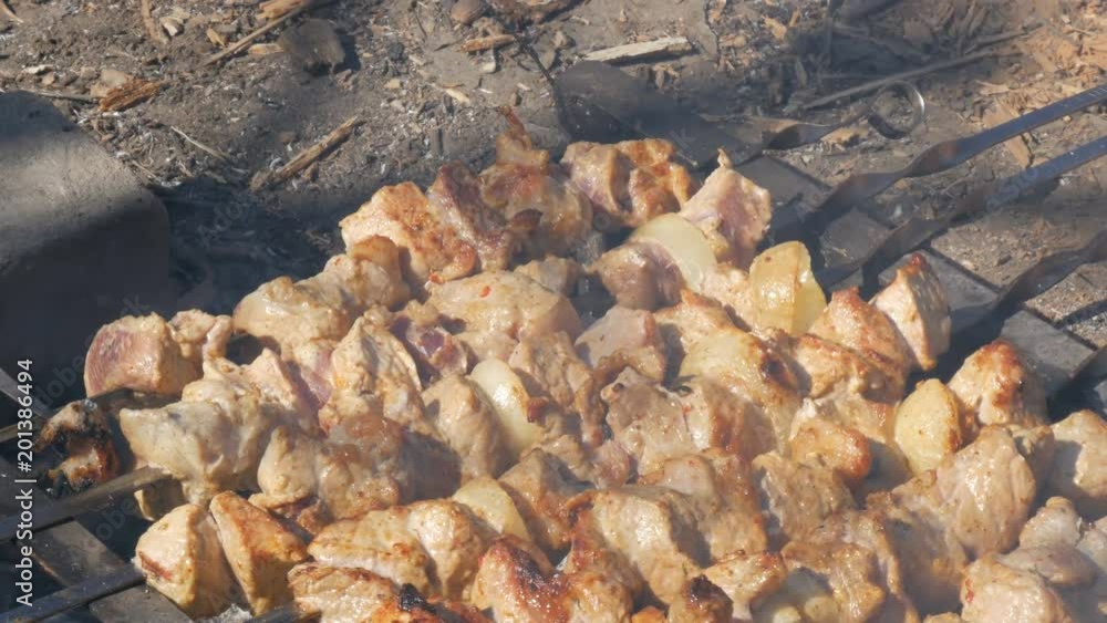 Lot of pieces of meat on skewers are roasted on a bonfire. A shish kebab or grilled meat is roasted in nature. A picnic in the countryside Lot of pieces of meat on skewers are roasted on a bonfire. A shish kebab or grilled meat is roasted in nature. A picnic in the countryside