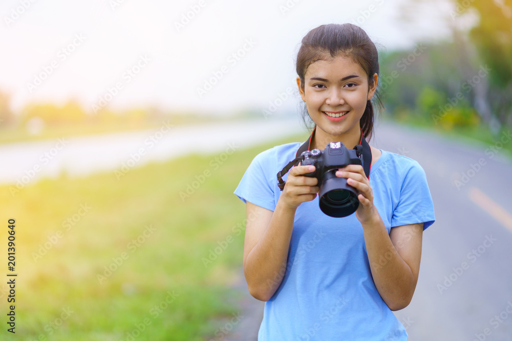 Portrait of beautiful girl in blue t-shirt and jeans smiling with a camera on hands