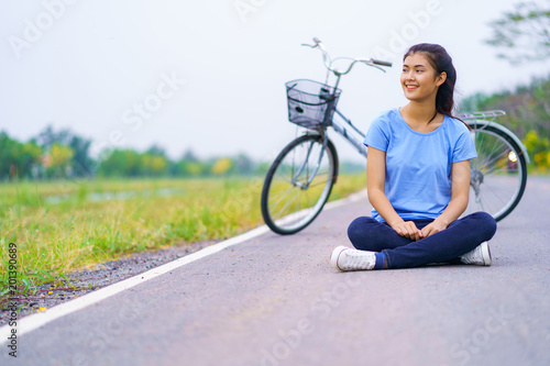 Girl with bike, Woman sitting on the road in the park and a bicycle