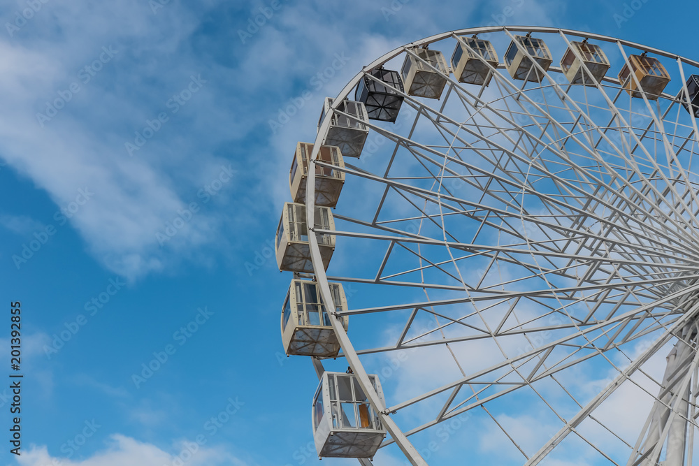 Big ferris wheel against blue sky wiht clouds from below. Emty.