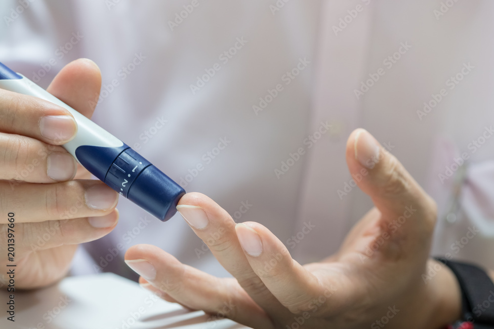 Close up of man hands using lancet on finger to check blood sugar level by Glucose meter using as Medicine, diabetes, glycemia, health care and people concept. Close up of man hands using lancet on finger to check blood sugar level by Glucose meter using as Medicine, diabetes, glycemia, health care and people concept.