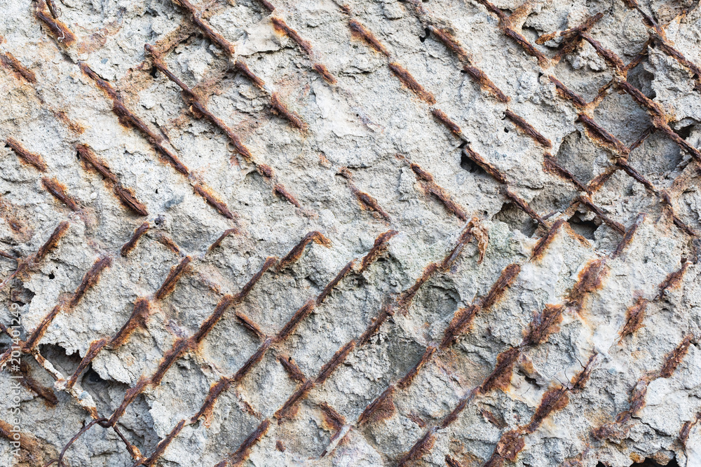 Fototapeta premium Textured background of an old concrete wall with a rusty outwardly extending reinforced armature. Close-up. Grunge background
