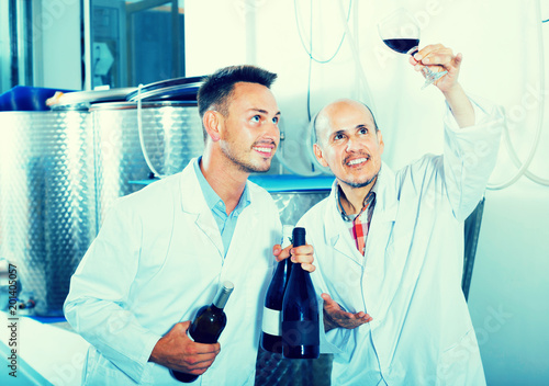 Two glad workers standing with glass of wine