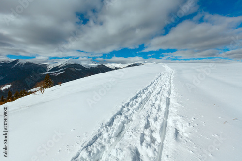 Sledge trace and footprints on winter mountain hill top photo