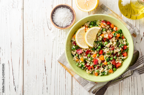 Fresh salad with bulgur and vegetables on white wooden table