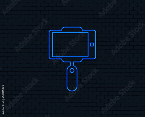 Neon light. Monopod selfie stick icon. Self portrait tool. Glowing graphic design. Brick wall. Vector