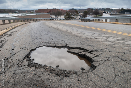 Pothole in road with broken asphalt after spring thaw