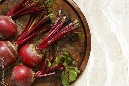 Fresh beetroots on metal tray on marble table with copy space right