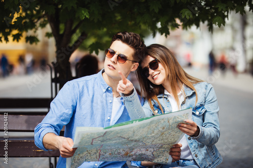 Young couple tourist with map pointing to a landmark backpackers in the city