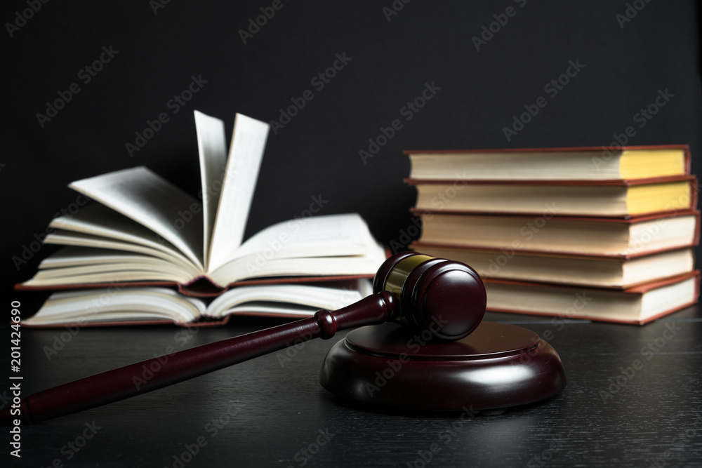 Judge gavel beside pile of books on wooden background Judge gavel beside pile of books on wooden background