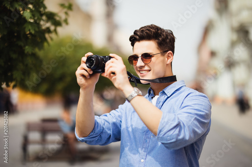 Portrait of happy young man, tourists with camera in the old city.
