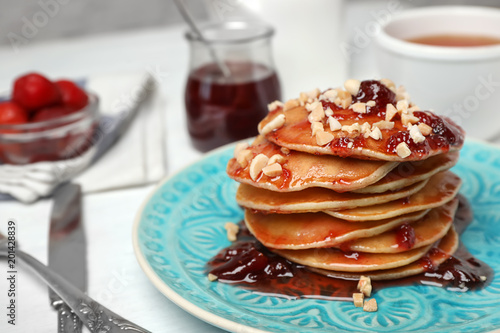 Delicious pancakes with jam and nuts on plate served for breakfast   closeup