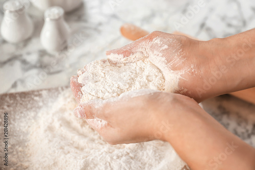 Woman holding flour over table, closeup