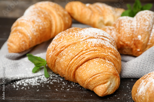 Tasty croissants with sugar powder on table, closeup