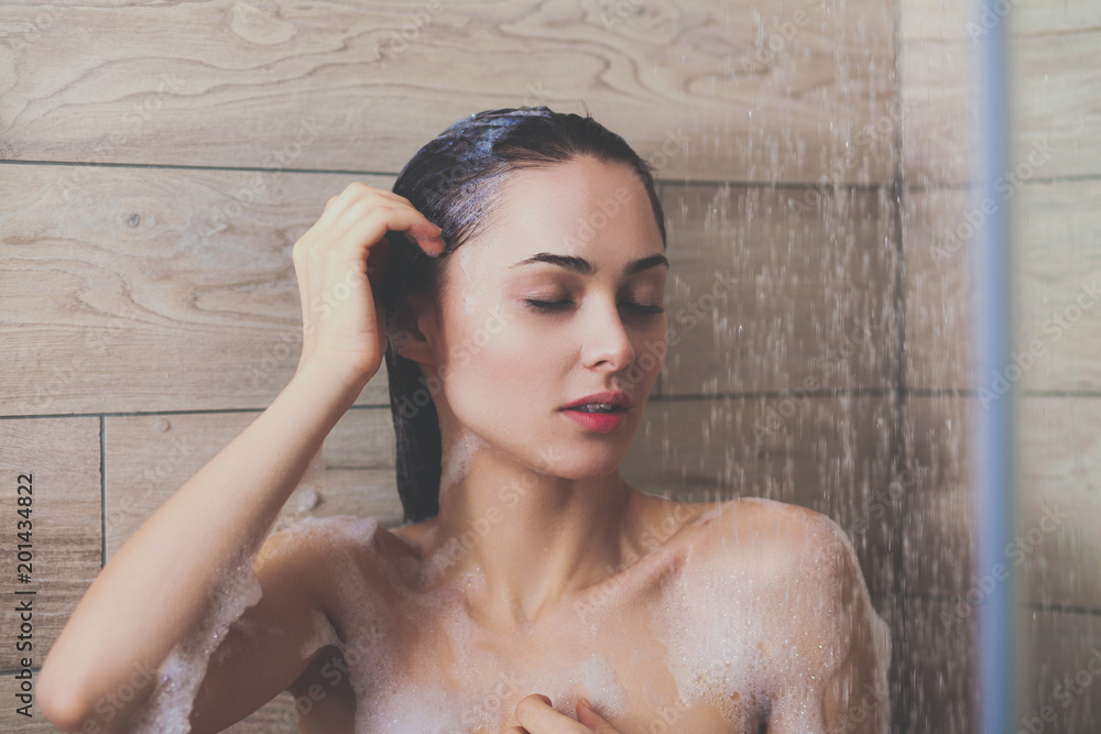 Naklejka premium Young beautyful woman under shower in bathroom.