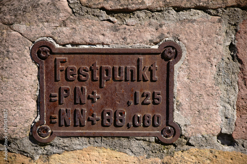 Festpunkt auf altem Gusseisen  / Ein Festpunkt beziehungsweise Vermessungspunkt zur Landschaftsvermessung in der Geodäsie.