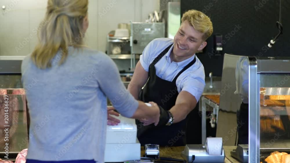 Butcher serving a mature woman in a butcher shop Butcher serving a mature woman in a butcher shop