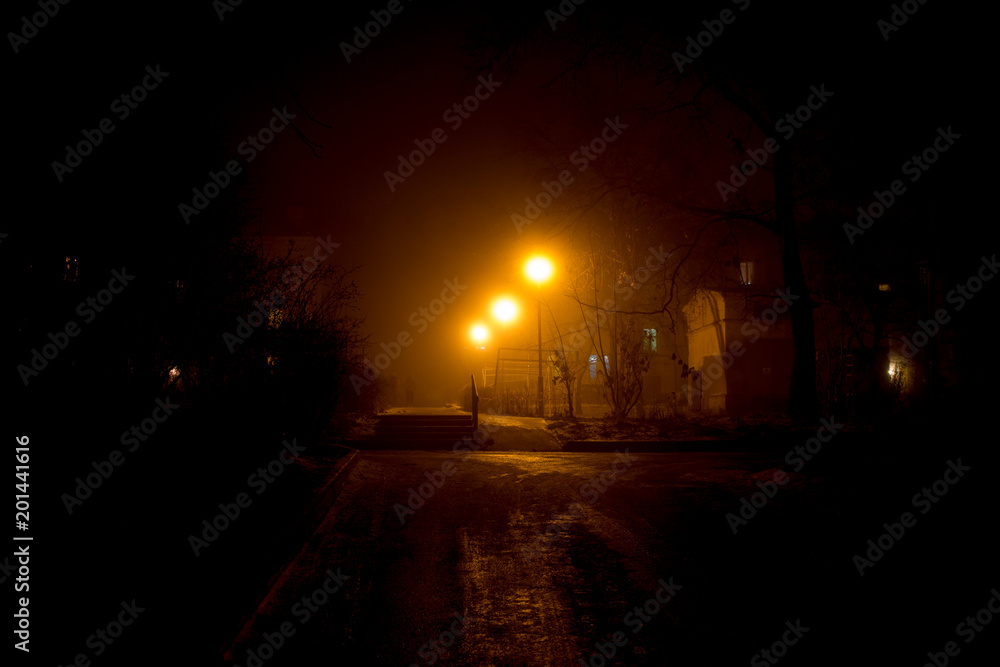 Dimly illuminated by street lamps, the urban courtyard, thick fog at night
