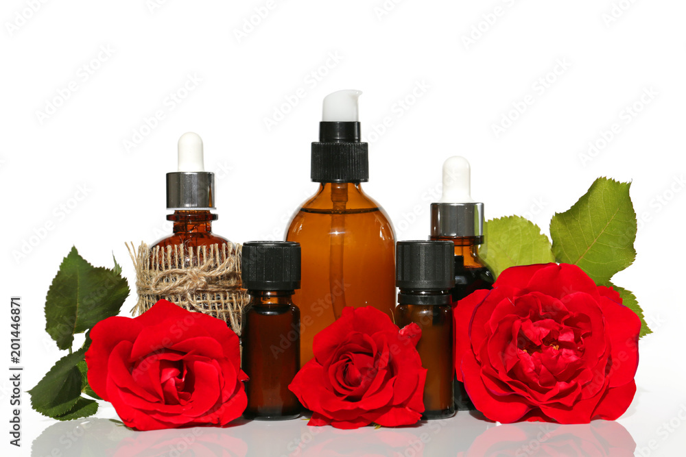 natural essential rose oil. rose oil set in brown glass bottles and large red rose on a white background. Organic Natural Oil natural essential rose oil. rose oil set in brown glass bottles and large red rose on a white background. Organic Natural Oil