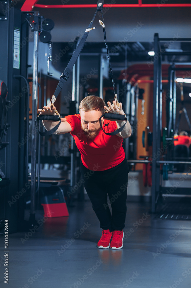 Fototapeta premium Strong woman using a resistance band in her exercise routine. Female athlete exercising with resistance band in studio.