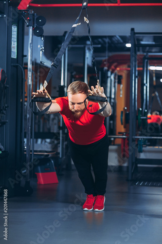 Strong woman using a resistance band in her exercise routine. Female athlete exercising with resistance band in studio.