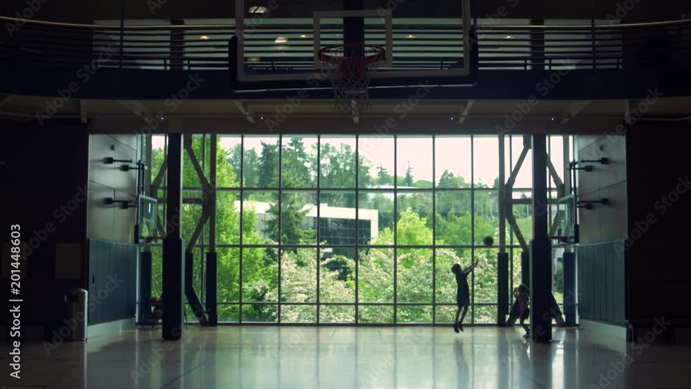 Two children playing basketball in a gym Two children playing basketball in a gym