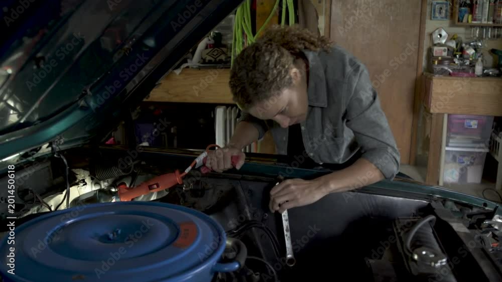 Mature woman working on car bonnet with wrench. Mature woman working on car bonnet with wrench.