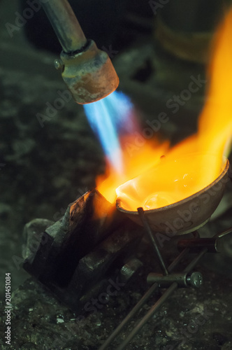 Craft jewelery making with professional tools. Macro shot. A handmade jeweler process, manufacture of jewellery. Melting metal photo