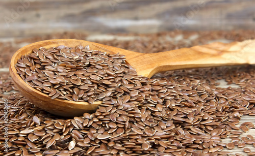 Flax seeds in wooden spoon on wooden background.