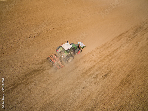 Aerial: ractor plows a agricultural field in spring and prepares it for sowing - aerial view