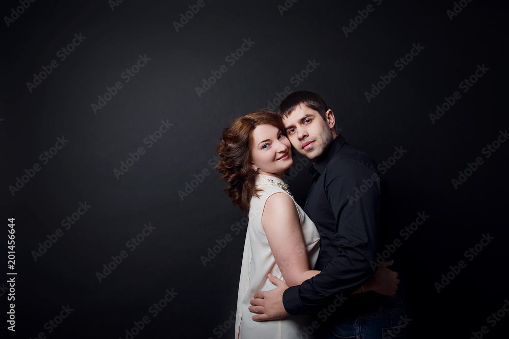 A married couple man and woman hugging each other against a black isolate. A married couple man and woman hugging each other against a black isolate.