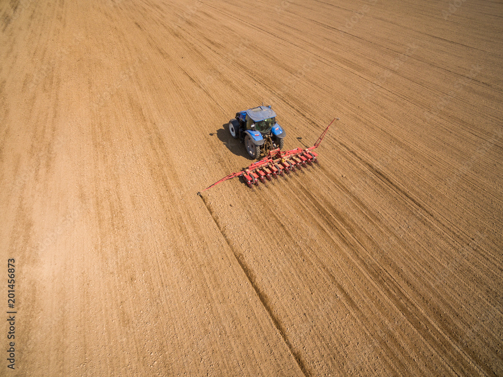 aerial view - Farmer with a tractor on the agricultural field sowing.  tractors working on the agricultural field in spring