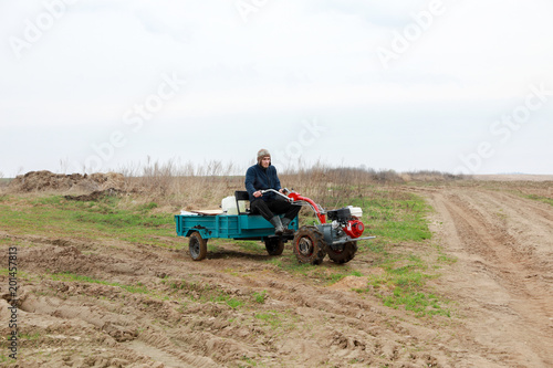 farmer on a small tractor with a trailer