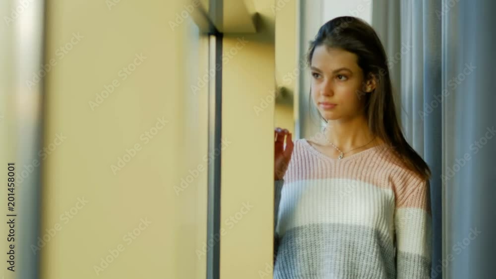 young beautiful woman. home leisure pastime. standing at the window looking out young beautiful woman. home leisure pastime. standing at the window looking out