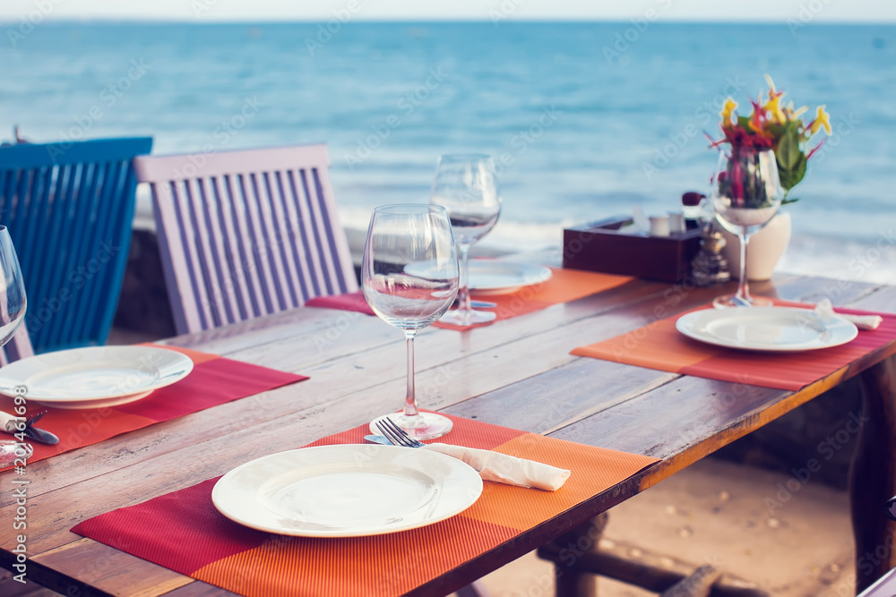 A romantic dinner in summer on a beach at sunset with two glasses of wine